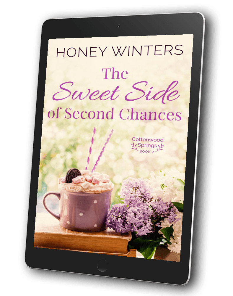 Book cover for The Sweet Side of Second Chances by Honey Winters. A pink mug of fancy coffee on a stack of books near a bouquet of lilacs.